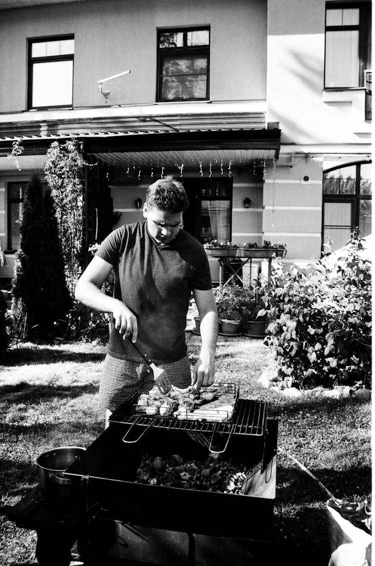 Man Grilling Barbeque At A Backyard