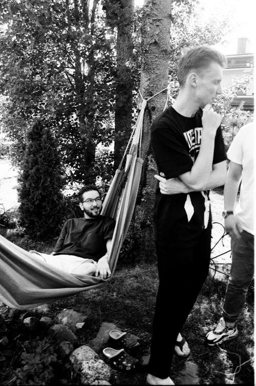 Free Three men enjoying a relaxed moment outdoors, one lounging in a hammock. Stock Photo