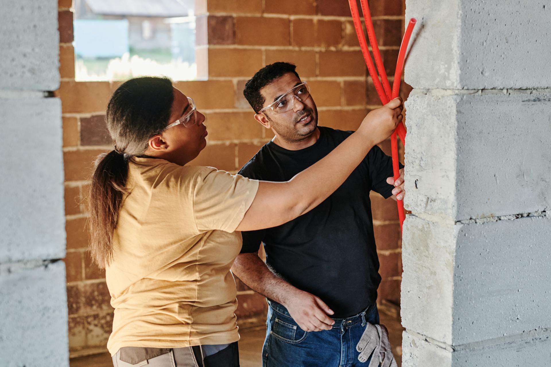 A Man and a Woman Wearing Goggles Holding Red Pipes