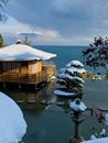 Brown Wooden House on Snow Covered Ground Beside Body of Water
