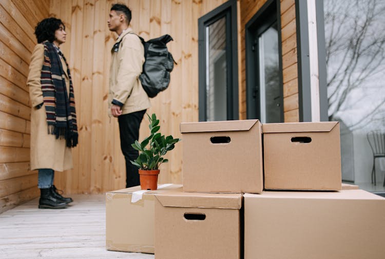 Man And Woman Having Conversation While Standing Near Carboard Boxes