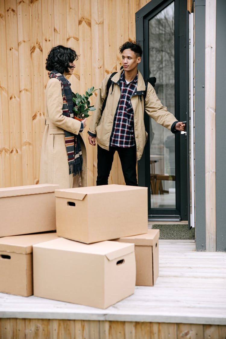 A Couple Standing On The Porch Of A Wooden House With Boxes