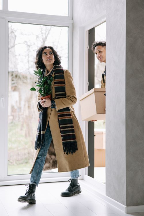 Free A joyous couple carrying items into their new house, symbolizing new beginnings. Stock Photo