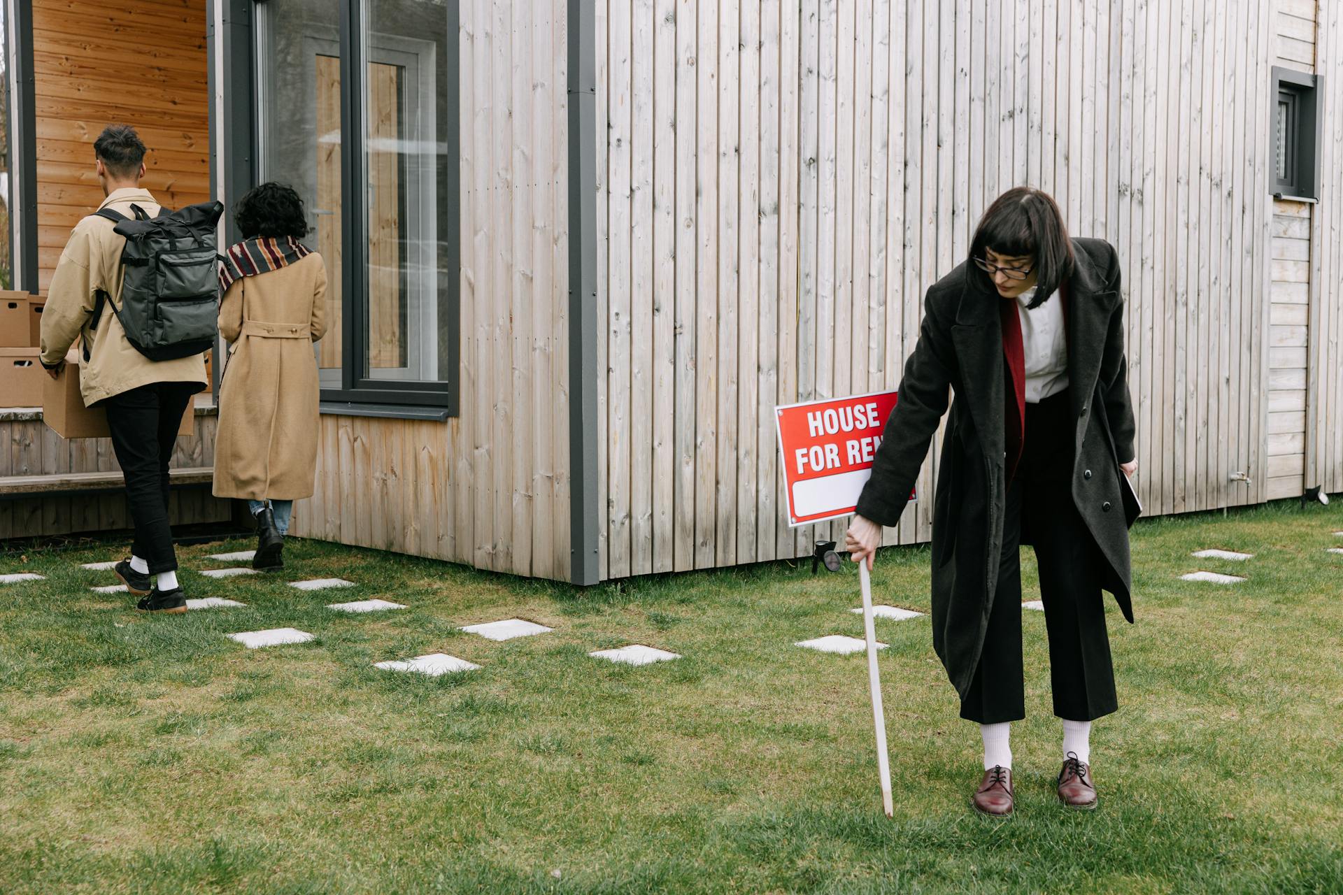 A Woman in Black Coat Holding a Placard on the Yard