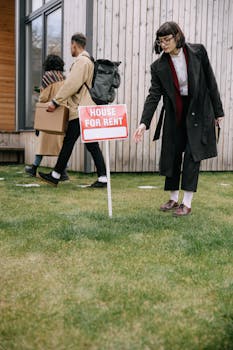 A group of adults inspecting a house for rent sign outside an apartment building while moving in.