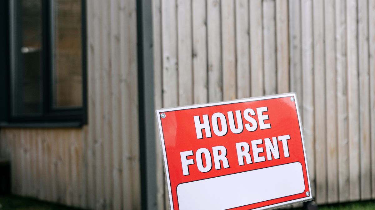 A red House for Rent sign outside a house with timber cladding