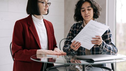 Two women reviewing real estate documents, indicating a decision or agreement indoors.