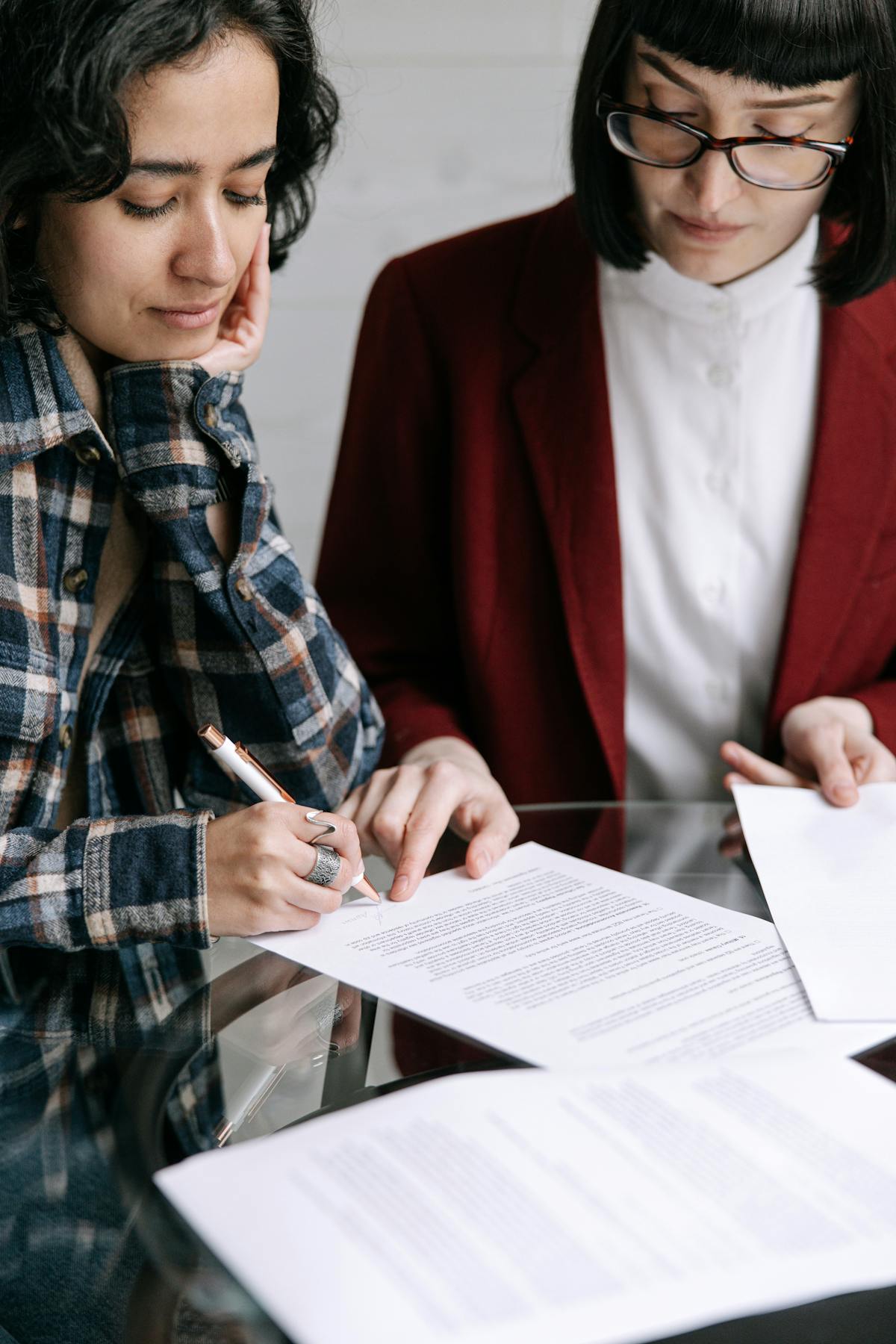 Due donne sedute al tavolo che firmano documenti durante consulenza