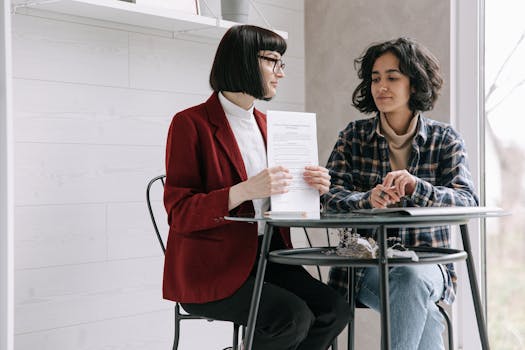 Two women reviewing real estate documents indoors, symbolizing a sale.