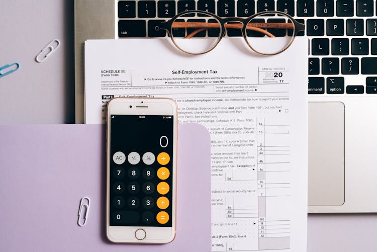 A Smartphone With A Calculator App Over A Tax Document