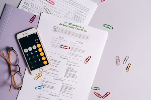 Top view of accounting essentials including smartphone, eyeglasses, and paperwork.