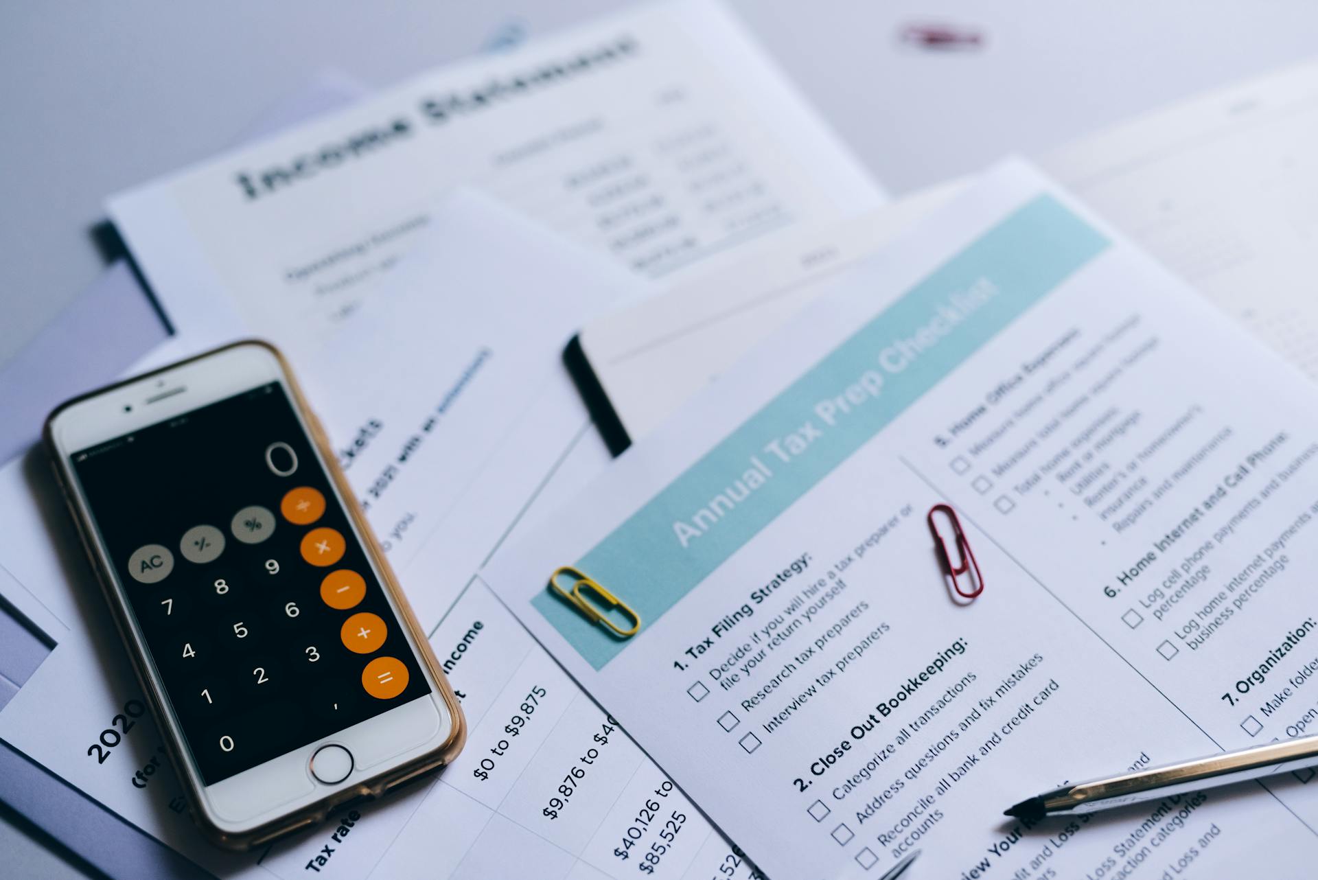 Tax preparation setup with documents, smartphone calculator, and checklist.