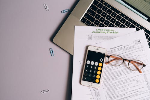 Free A Mobile Phone and Eyeglasses on Top of the Documents Near the Laptop Stock Photo