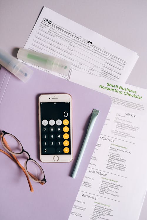 Free A Smartphone Calculator and Eyeglasses on a Purple Folder Stock Photo