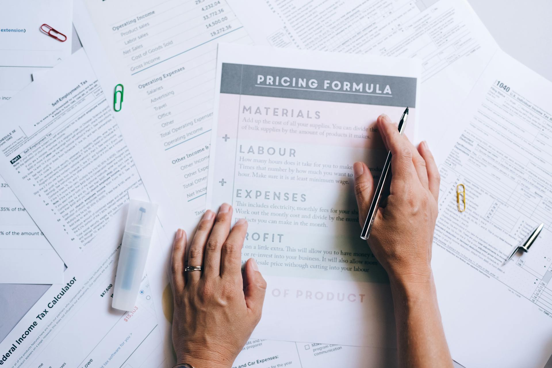 A Person Holding a Pen while Touching the Documents on the Table