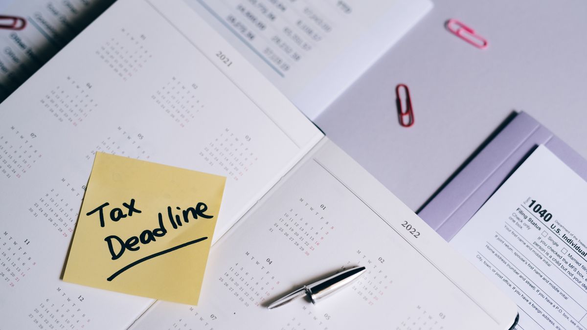 A calendar with a tax deadline note and tax forms, emphasizing organization.