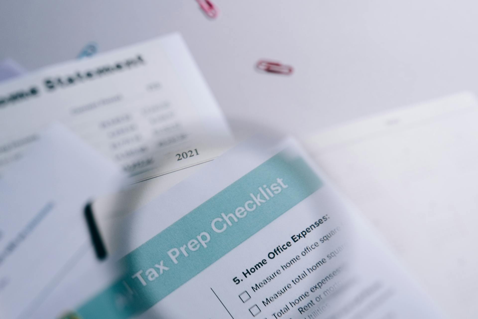 Close-up of tax preparation checklist and income statement with paperclips.