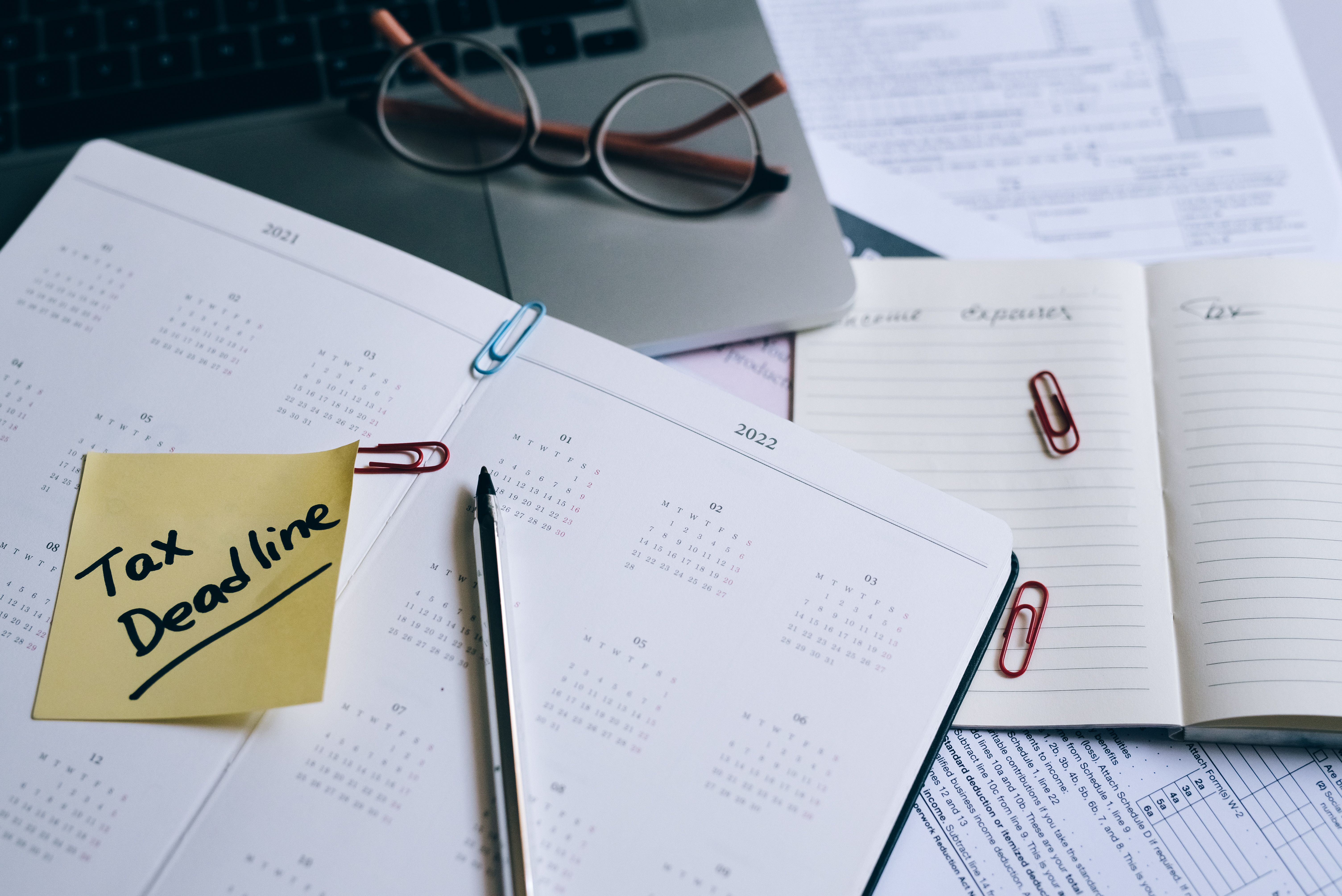QBCC Licence Renewal: Deadlines, Fees and What Happens If You Miss It 2 Desk planner with a deadline reminder sticky note, glasses and paperwork