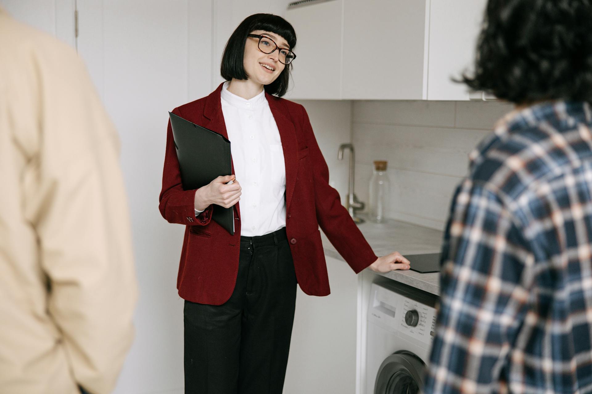 Real estate agent with clients in a modern kitchen during apartment viewing. Professional and engaging.