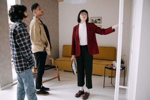 Realtor guiding potential buyers through a stylish apartment viewing.