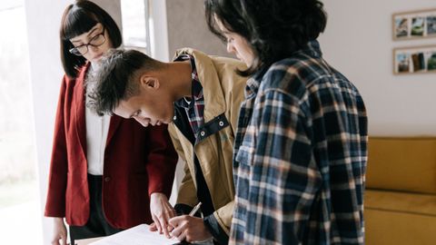 Young couple signing a real estate agreement with an agent indoors.