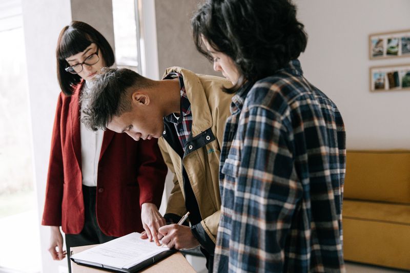 Young couple signing a real estate agreement with an agent indoors.