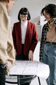 Real estate agent explains floor plans to clients during a property tour indoors.