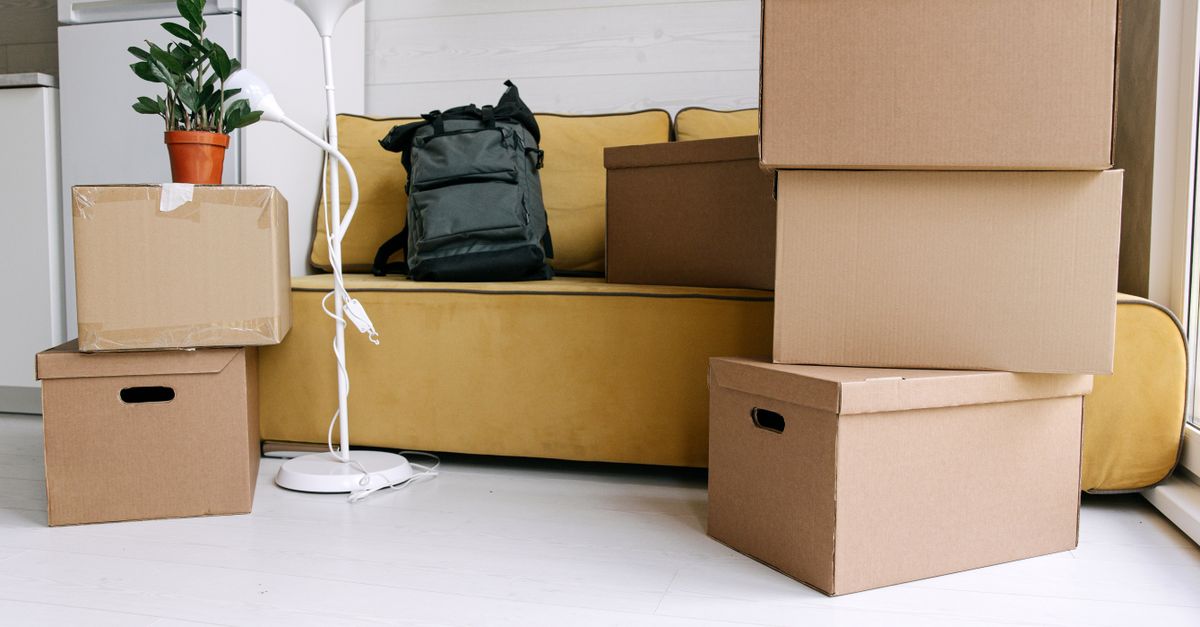 Cardboard boxes and a backpack in a cozy living room signify moving day excitement.