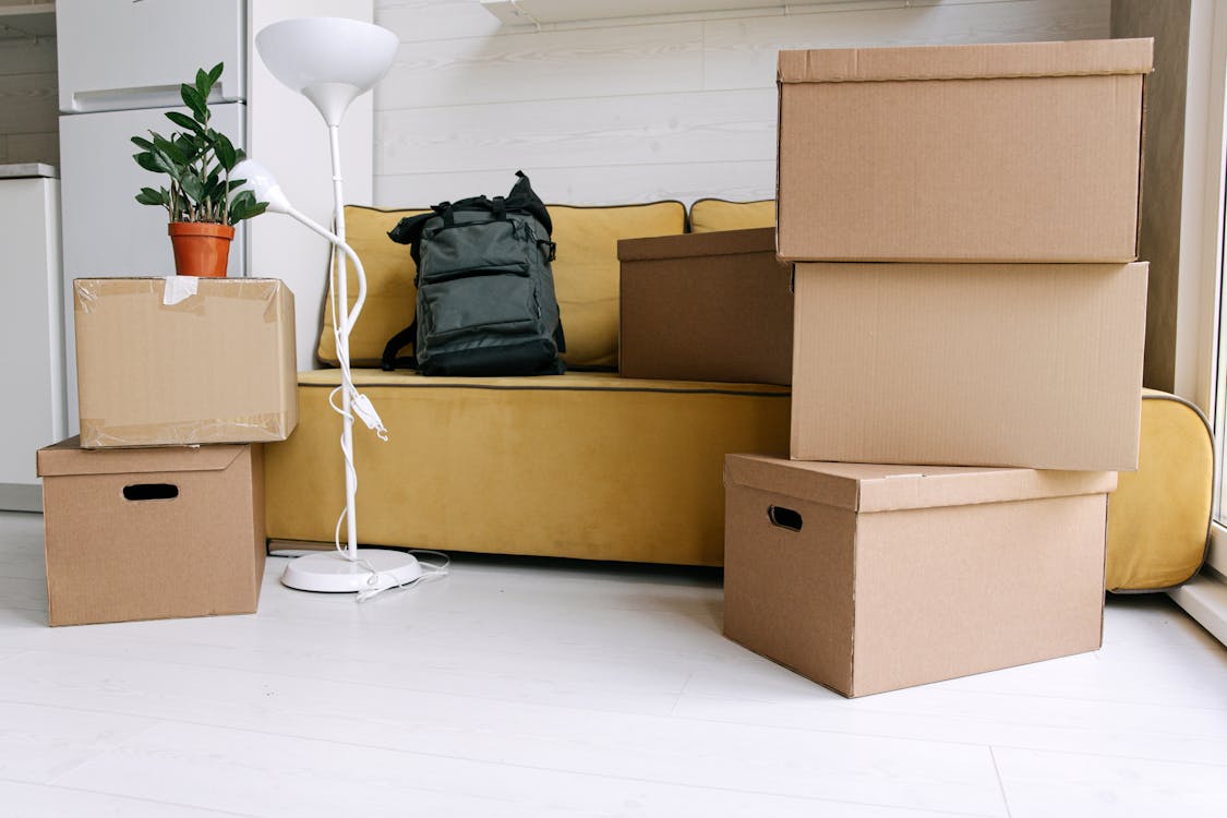 Black Backpack on Yellow Couch Beside Boxes
