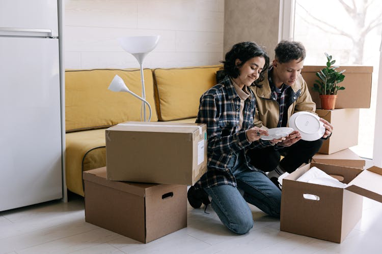 A Couple Unpacking Boxes In Their New House 