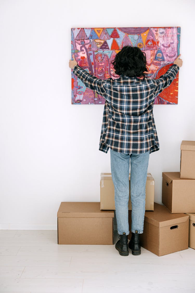 Back View Of A Person Putting A Painting On The Wall