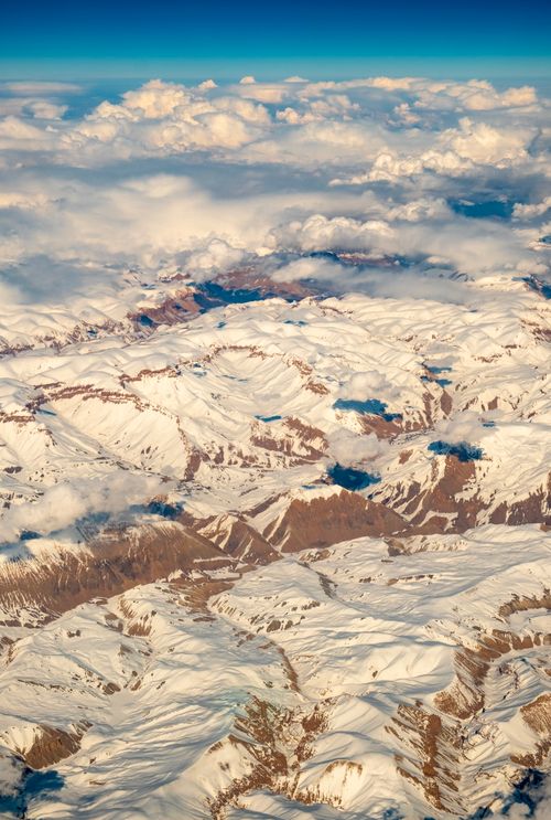 Free An aerial view of snow-covered mountains under a clear sky, showcasing winter's natural beauty. Stock Photo