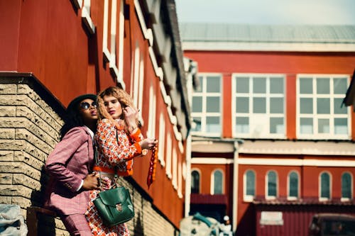 Selective Focus Photographed of Woman Wearing Orange and White Floral Dress and Man Wearing Maroon Suit