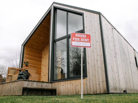 Low-angle view of a modern wooden house with a 'House for Rent' sign, showcasing contemporary architecture.