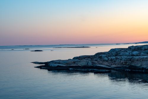 Free Tranquil ocean scene with rock formations and a vibrant sunset along the coast. Stock Photo