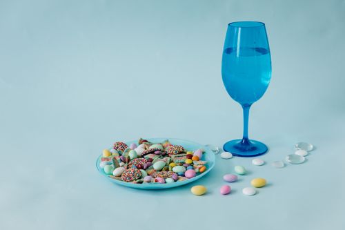Free Colorful candies and a blue glass on pastel background, shot in studio. Stock Photo