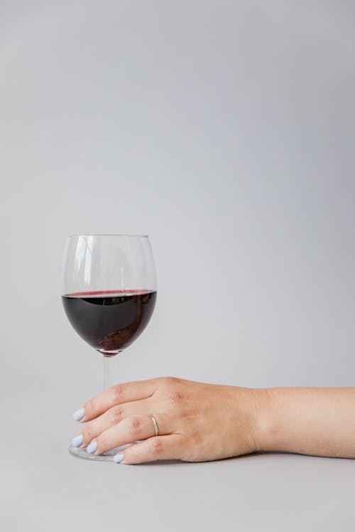 Close-Up Shot of a Person Holding a Glass of Red Wine