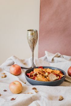 A bowl of dried fruit with apples on a textured cloth, embodying natural elegance.