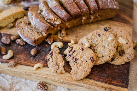Close-up of assorted baked goods, including breads and cookies, on a rustic wooden tray.