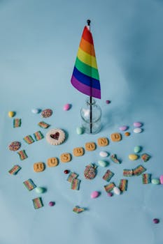 Bright assortment of candies with a rainbow flag on a light blue background.
