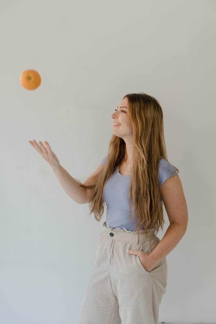 A Happy Young Woman Tossing An Apple