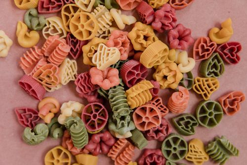 Free A vibrant mix of uncooked pasta in various shapes and colors, showcasing food diversity. Stock Photo