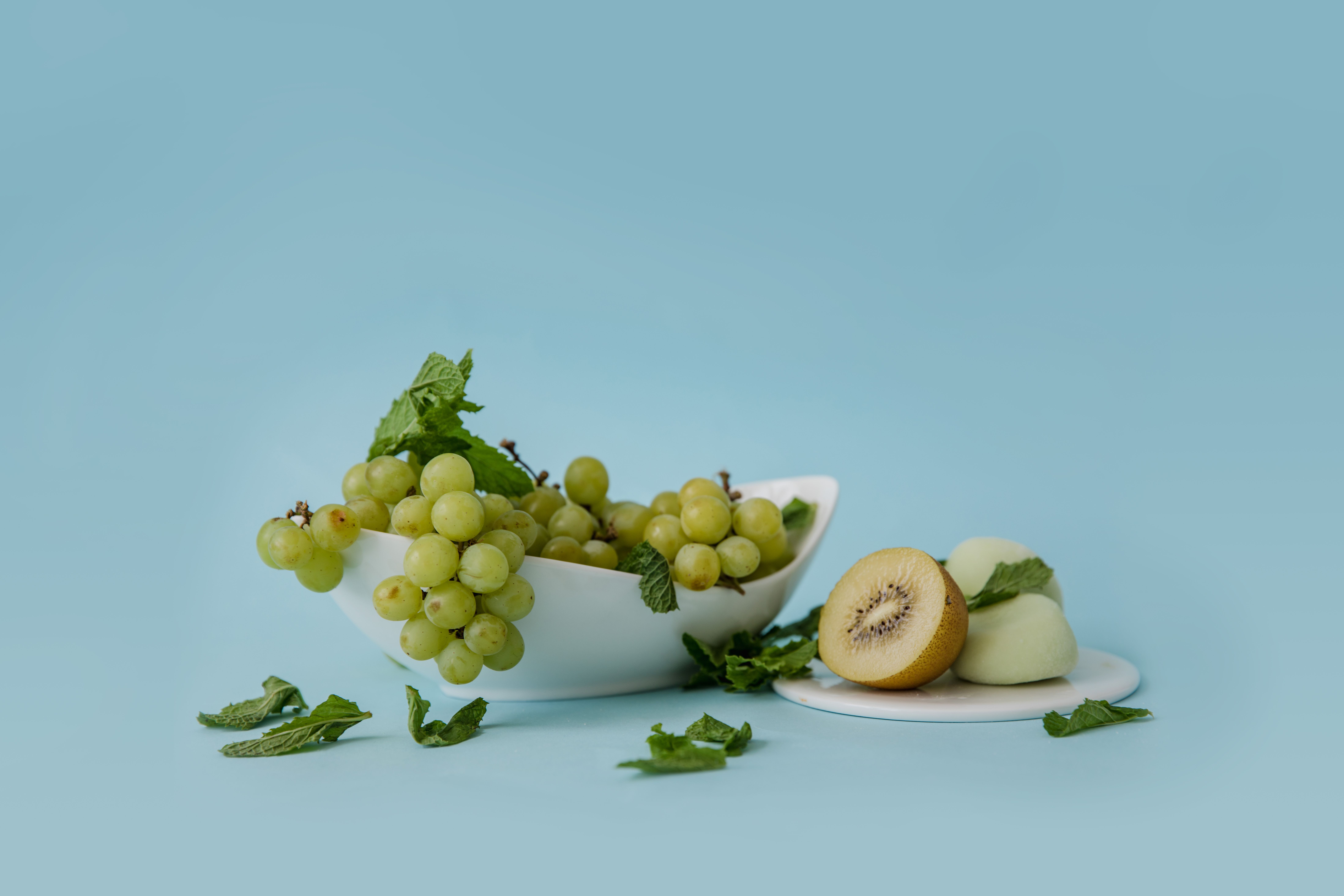 natural detoxification methods for a healthier body - Delightful arrangement of green grapes with kiwi slices and mint on pastel background.