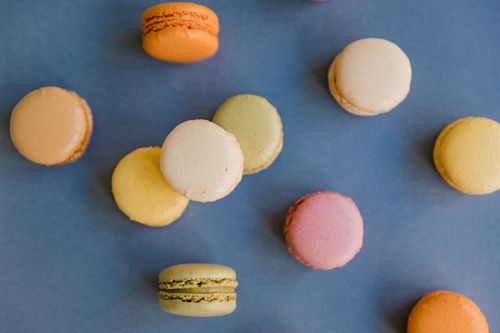Free Vibrant assortment of macarons arranged on a blue surface. Perfect for dessert enthusiasts. Stock Photo