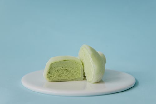 Free Creamy green tea mochi on a white plate against a pastel blue background. Stock Photo