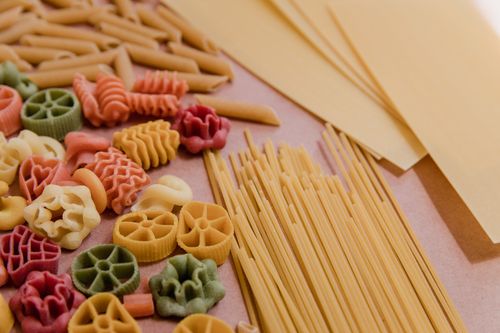 Free Vibrant selection of uncooked pasta shapes including spaghetti and fusilli on a tabletop. Stock Photo