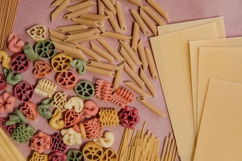 Free Colorful and diverse uncooked pasta variety on a flat surface, showcasing shapes and textures. Stock Photo