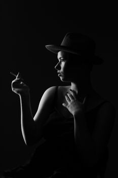 Artistic black and white portrait of a woman in a hat, elegantly holding a cigarette.