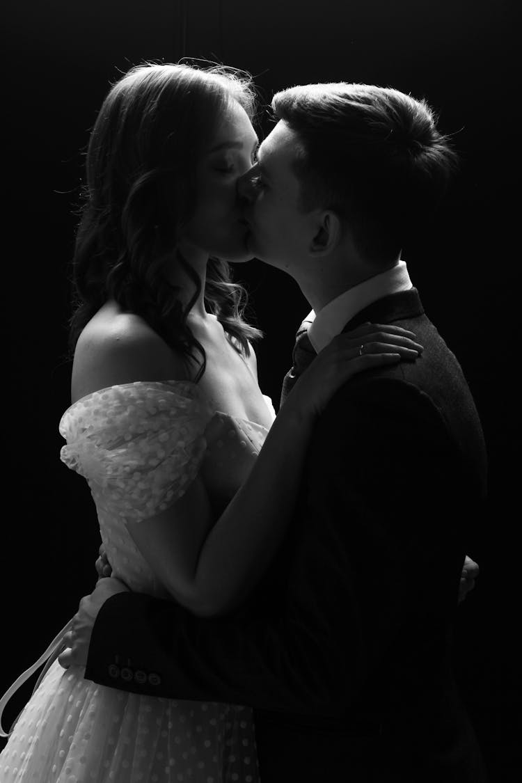 Man In A Suit Kissing Woman In An Off Shoulders Dress