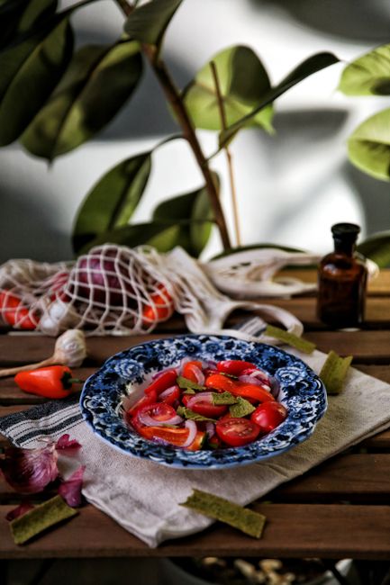 Colorful summer salad with tomatoes, peppers, and herbs on a wooden table.